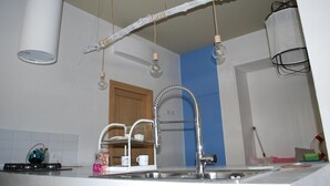 Una cocina con un grifo moderno, bombillas colgantes y una decoración de rama de madera.
