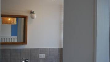 A modern bathroom with a white sink, a mirror, and a pendant light.