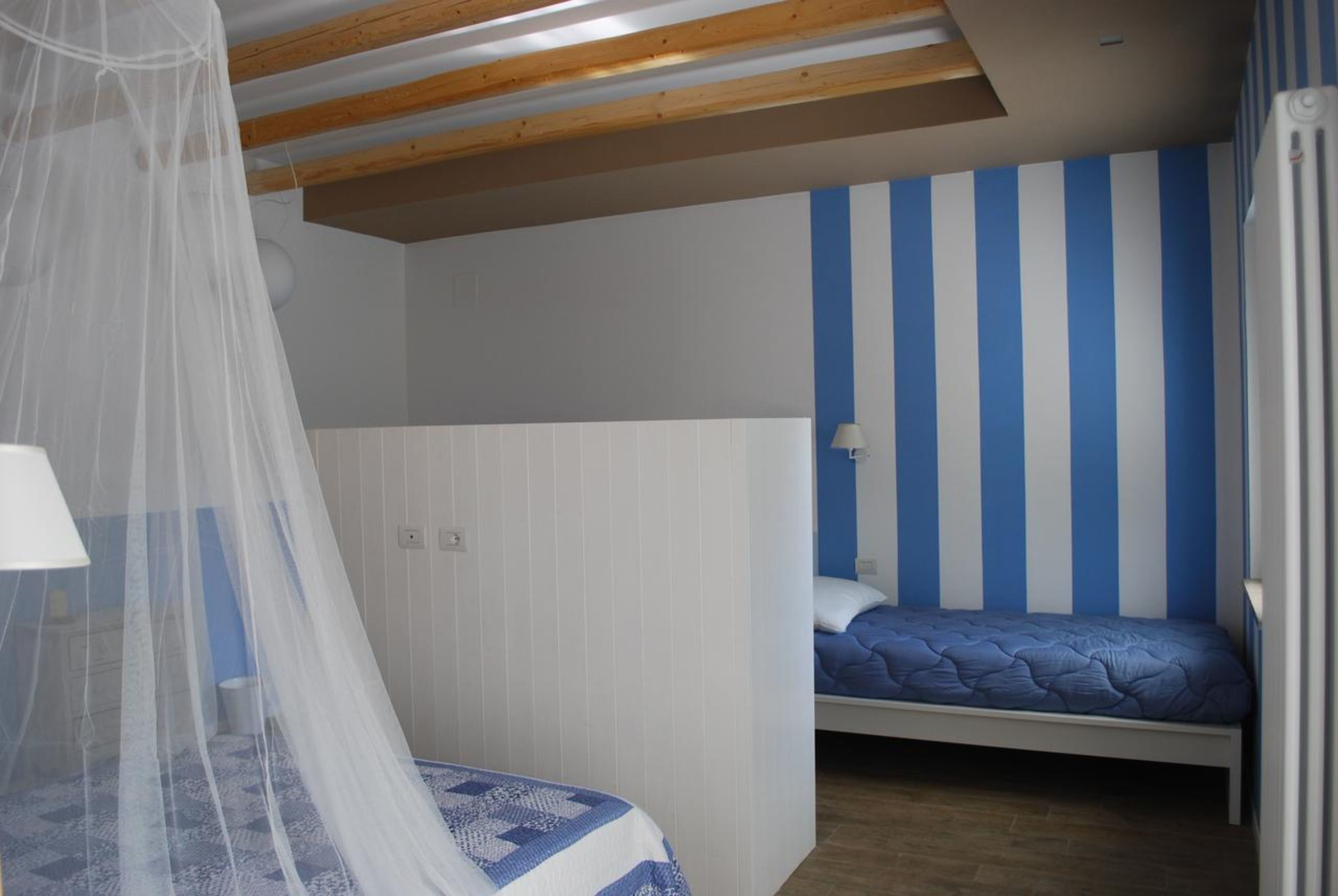 Ein Schlafzimmer mit Bett, Nachttisch, Lampe und einem Fenster mit Vorhängen.