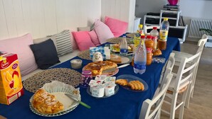 Una mesa de comedor con comida y bebidas, un sofá con cojines y un radiador al fondo.
