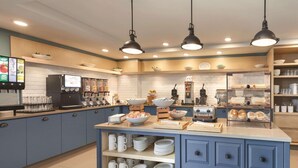 A modern kitchen with blue cabinets, a central island with bowls and utensils, and overhead pendant lighting. - Country Inn & Suites by Radisson, Ocean City, MD (Ocean City)