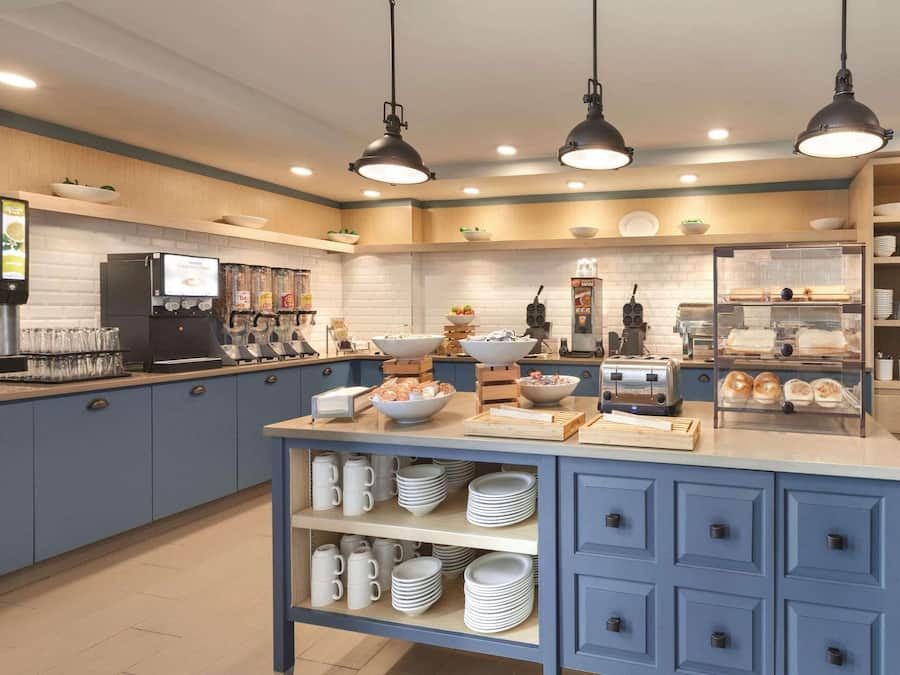 A modern kitchen with blue cabinets, a central island with bowls and utensils, and overhead pendant lighting.