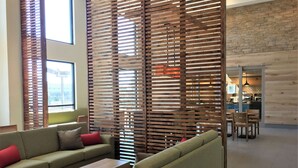 A modern living area with two sofas, a coffee table, and a wooden partition. - Country Inn & Suites by Radisson, Ocean City, MD (Ocean City)