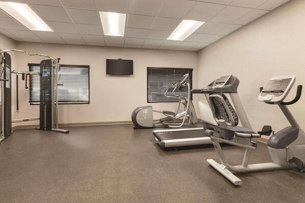A fitness room with treadmills, elliptical machines, and a weight machine.
