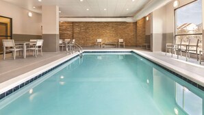 A swimming pool with chairs and tables around it, a brick wall, and a large window. - Country Inn & Suites by Radisson, Ocean City, MD (Ocean City)