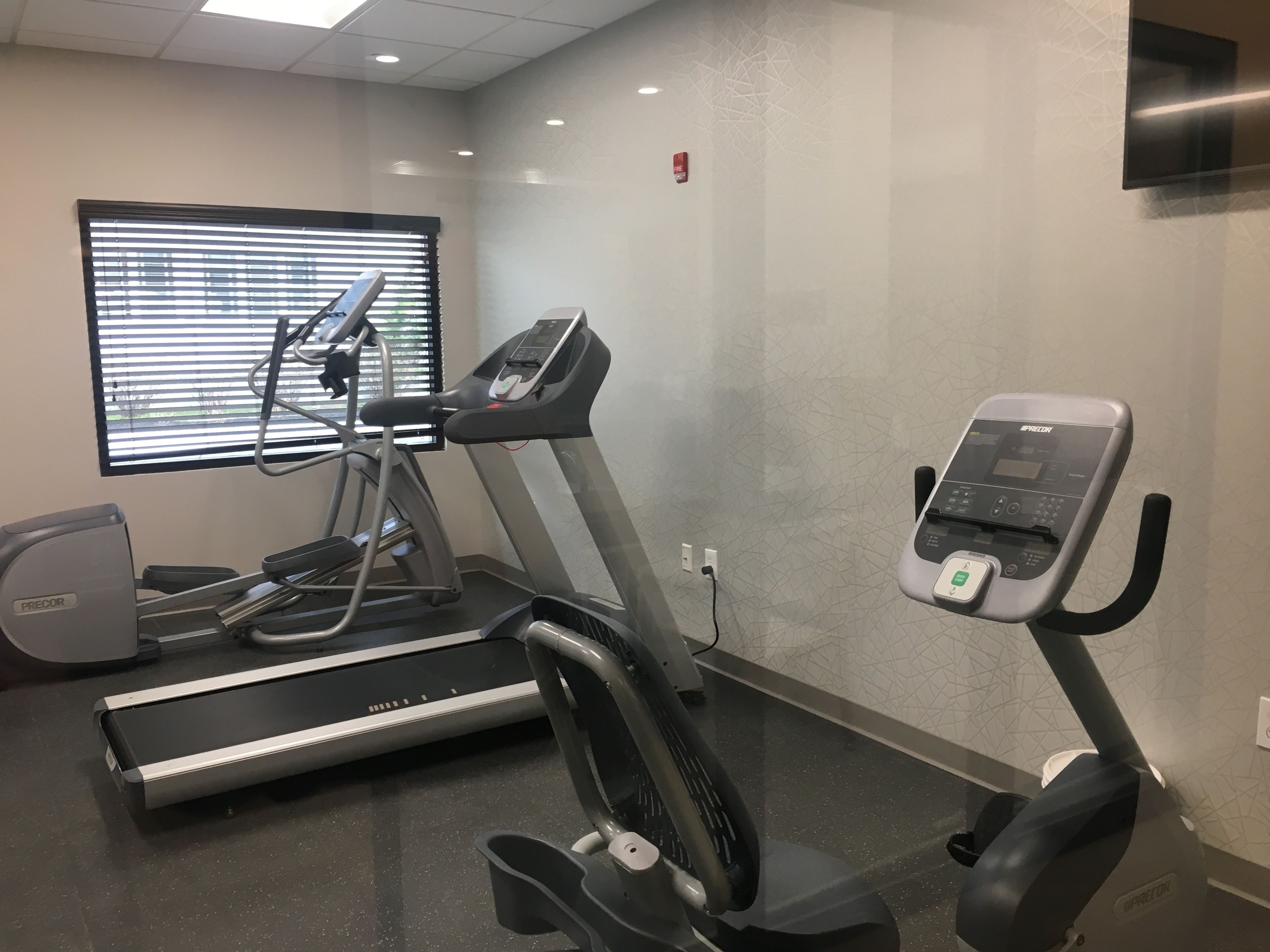 A gym with treadmills, a stationary bike, and a wall-mounted exercise machine.