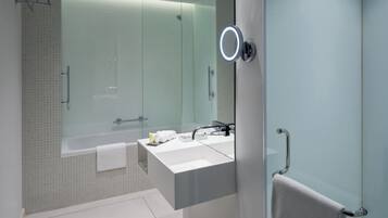 Un baño moderno con cabina de ducha de vidrio, tocador blanco y un perchero para toallas.