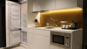 Uma cozinha moderna com frigorífico embutido, pia dupla, micro-ondas e máquina de café.