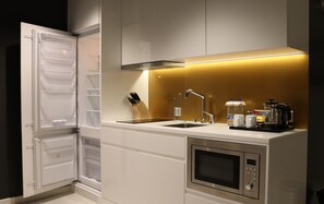 Een moderne keuken met een geïntegreerde koelkast, een dubbele spoelbak, een magnetron en een koffiezetapparaat.