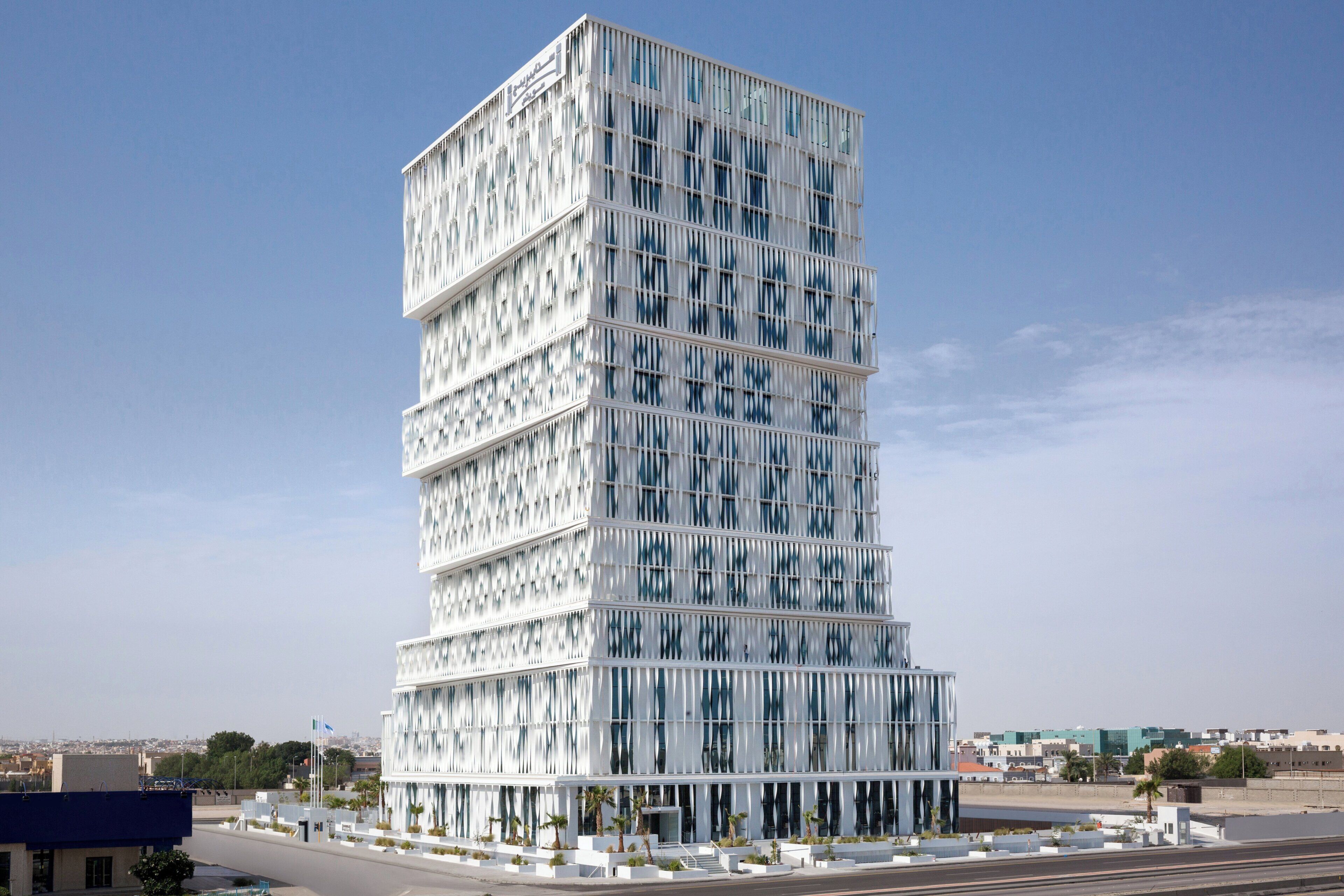 Un edificio moderno de varios pisos con una fachada distintiva de listones verticales.