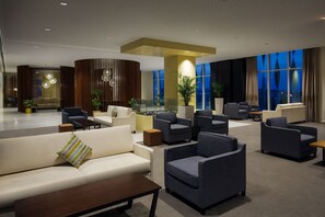 Een moderne lobby met zithoeken, een receptiebalie en grote ramen met uitzicht over de stad.