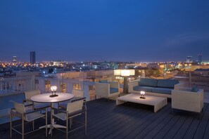 Una terrazza sul tetto con posti a sedere all'aperto e vista sulla città al crepuscolo.