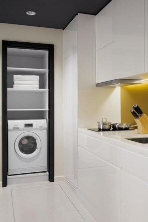 Een moderne keuken met witte kasten, een ingebouwde wasmachine en een spoelbak met messenblok.