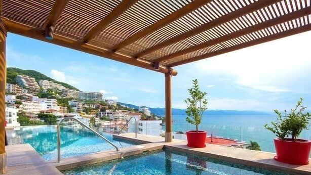 A rooftop infinity pool with a wooden pergola, red planters, and a view of a coastal town. - Romantic Zone V177 1 Bedroom (Puerto Vallarta)