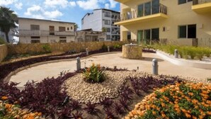 A landscaped courtyard with a central circular flower bed, surrounded by a low stone wall. - Romantic Zone V177 1 Bedroom (Puerto Vallarta)