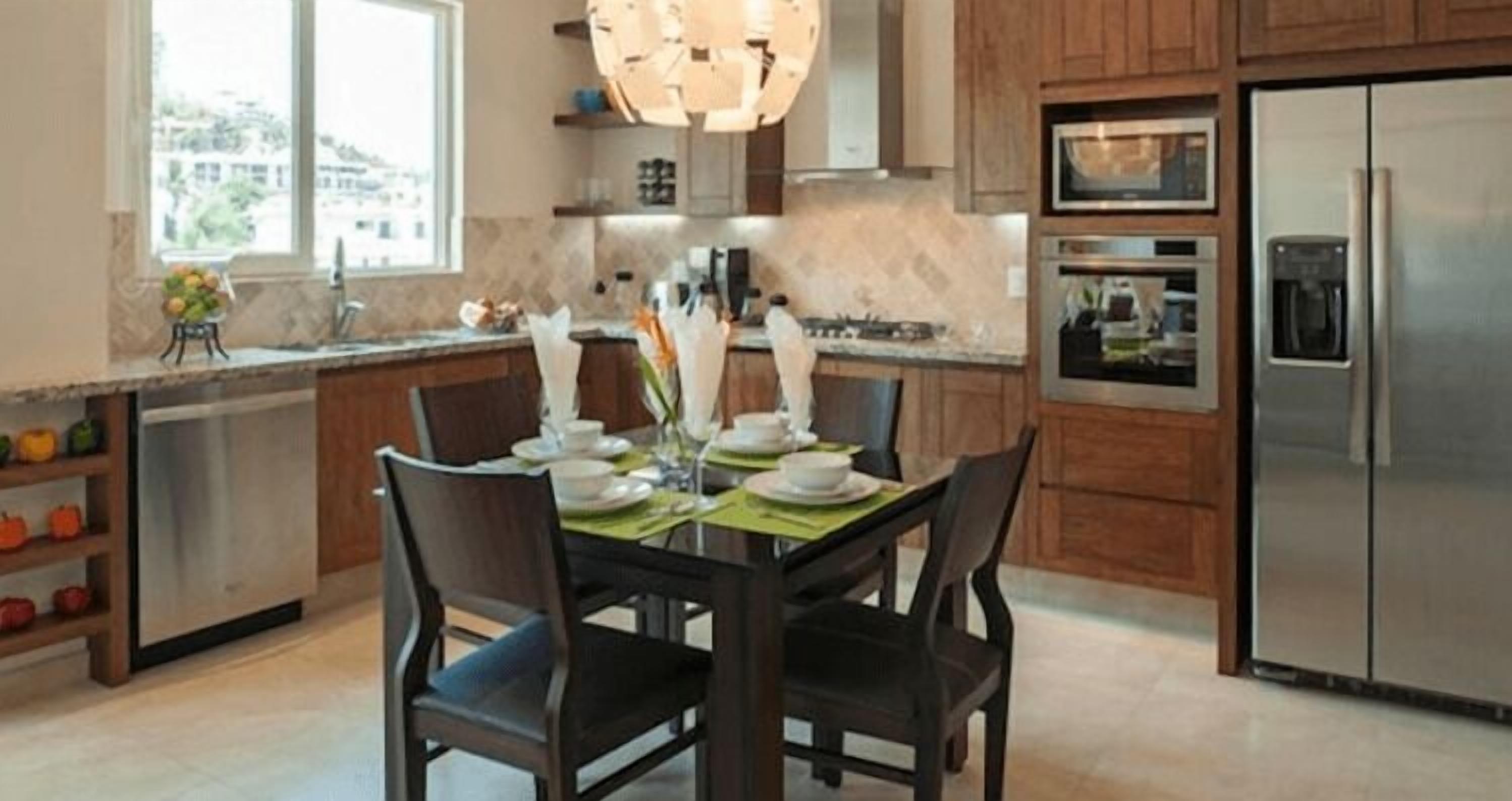 Una cocina moderna con armarios de madera, electrodomésticos de acero inoxidable y una zona de comedor para cuatro.