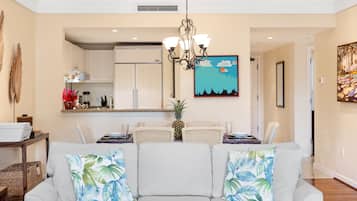 Un salon comprenant un canapé, un lustre et un coin repas avec des chaises et une table.