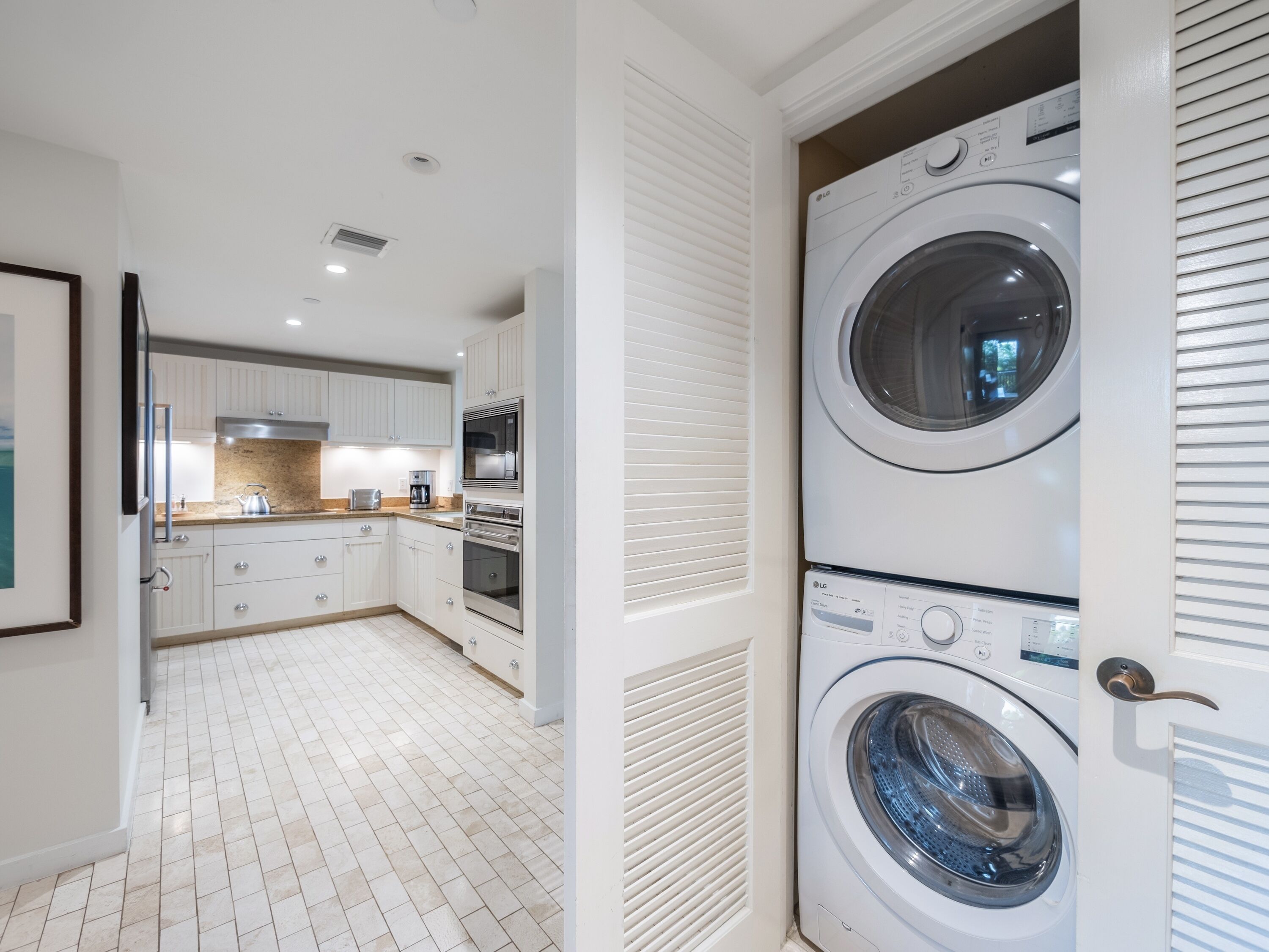A modern kitchen with white cabinetry, a built-in oven, and a microwave.