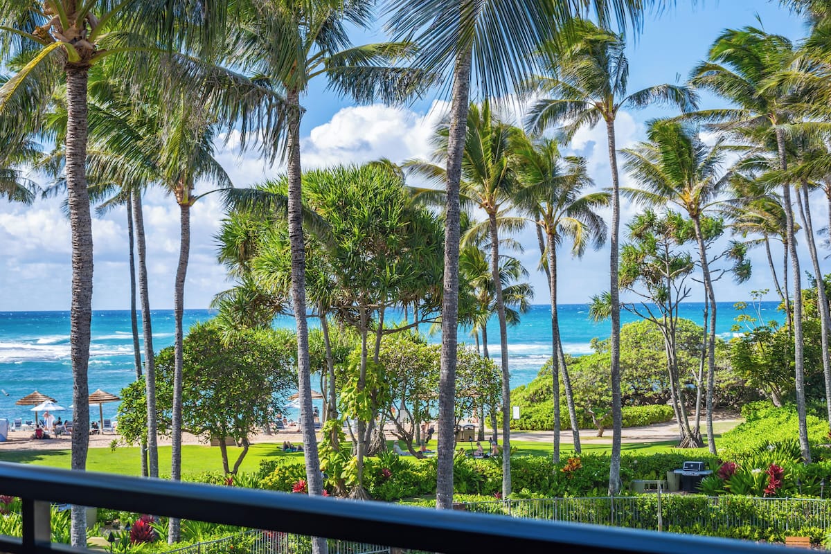 Un resort tropical con palmeras, una zona de piscina y vista al océano.