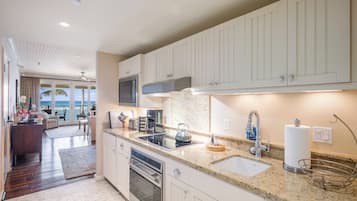 A modern kitchen with white cabinets, a granite countertop, and stainless steel appliances.