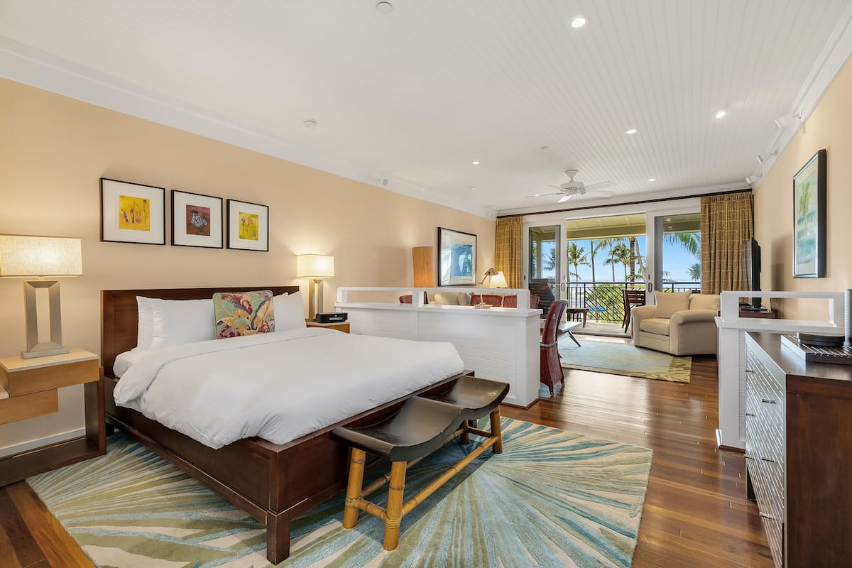 Una habitación de hotel moderna con una cama grande, un escritorio y vistas a palmeras a través de las puertas del balcón.