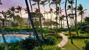 A resort with a swimming pool, lounge chairs, palm trees, and a pathway. - Oceanfront Vacation Villas at Turtle Bay (Kahuku)