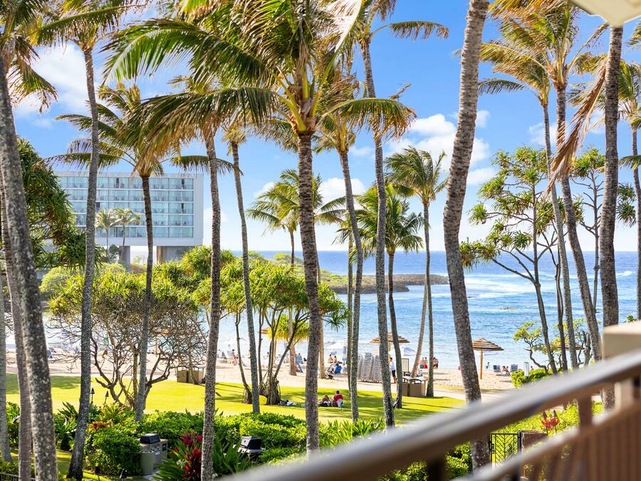 A view of a beach with palm trees and a building in the background.