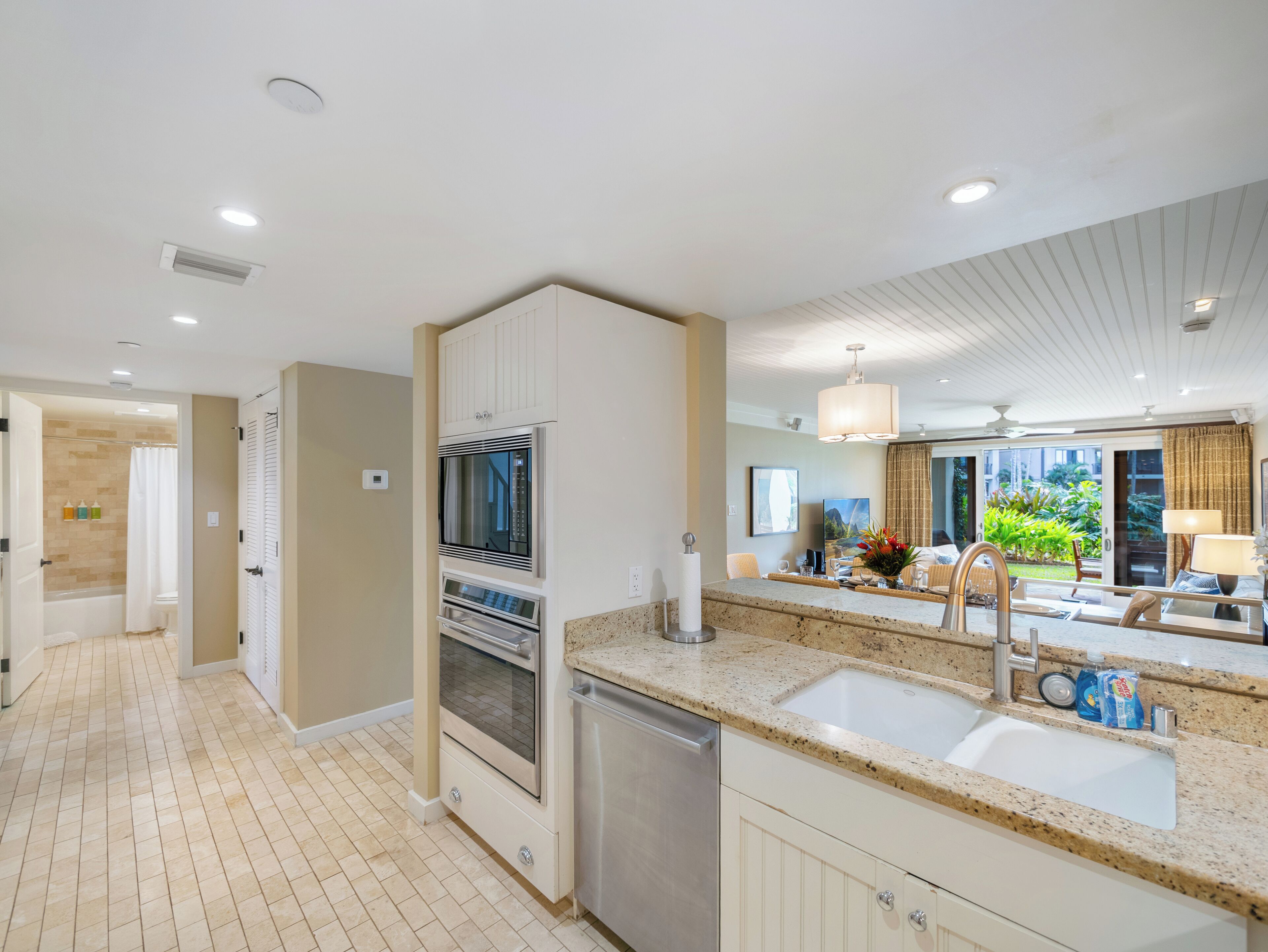 A modern kitchen with built-in appliances, a large island with a sink, and a view of the outdoor garden.