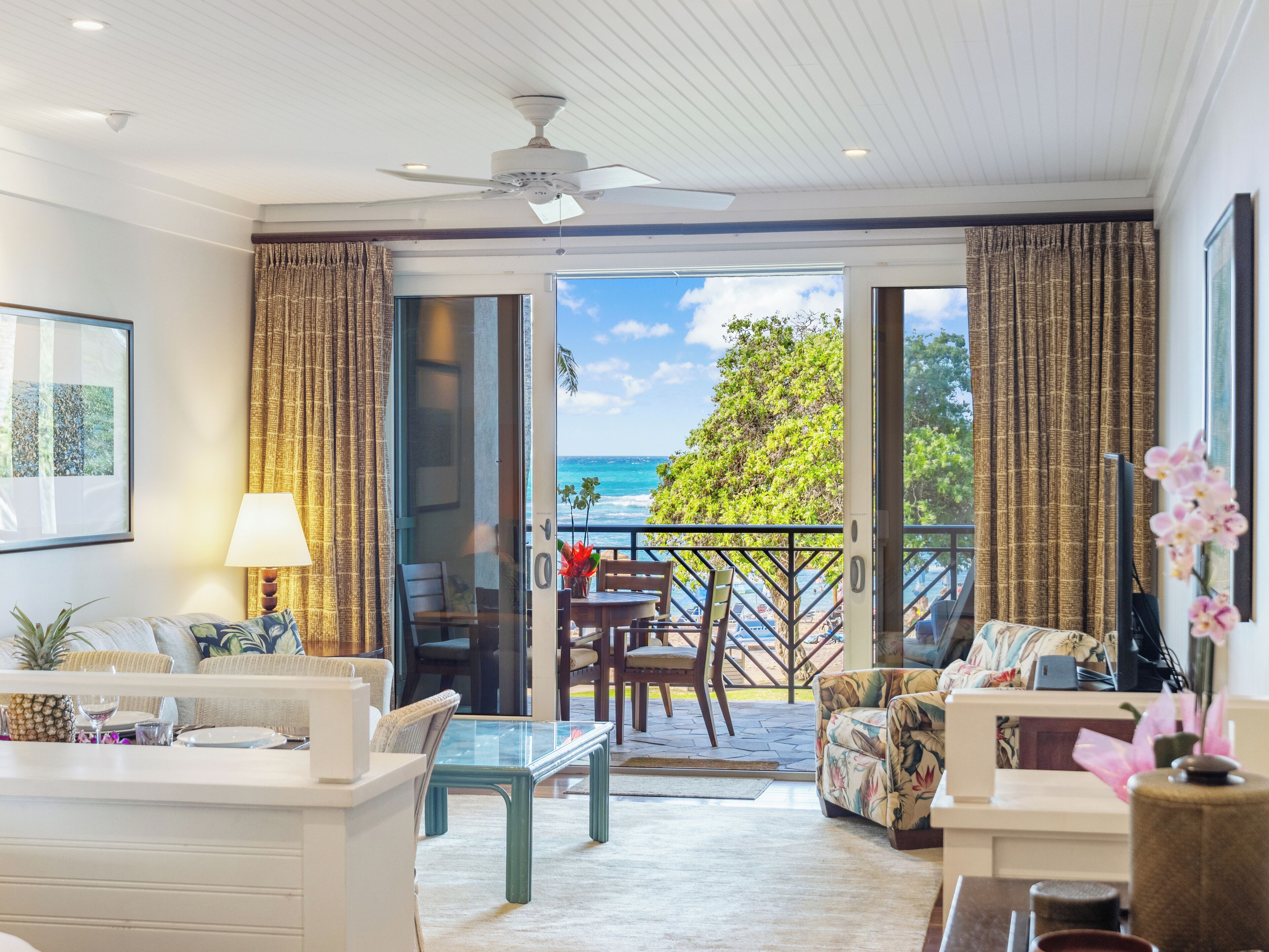 Ein modernes Wohnzimmer mit Glastür zum Balkon, der Blick auf das Meer bietet.