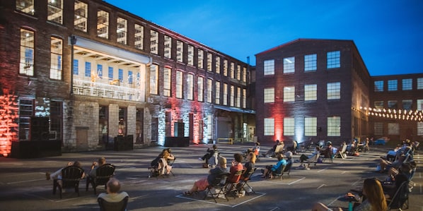 An outdoor seating area with people, a building with large windows, and a brick facade.