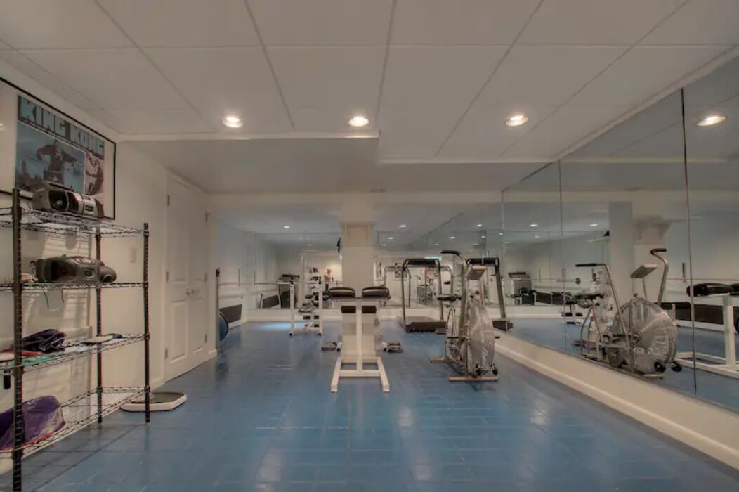 A gym with exercise equipment, a mirrored wall, and a blue floor.