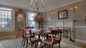 A dining room with a chandelier, a fireplace, and a large mirror.