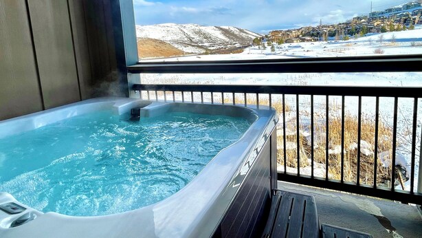 A hot tub with a view of a snowy landscape and a village.