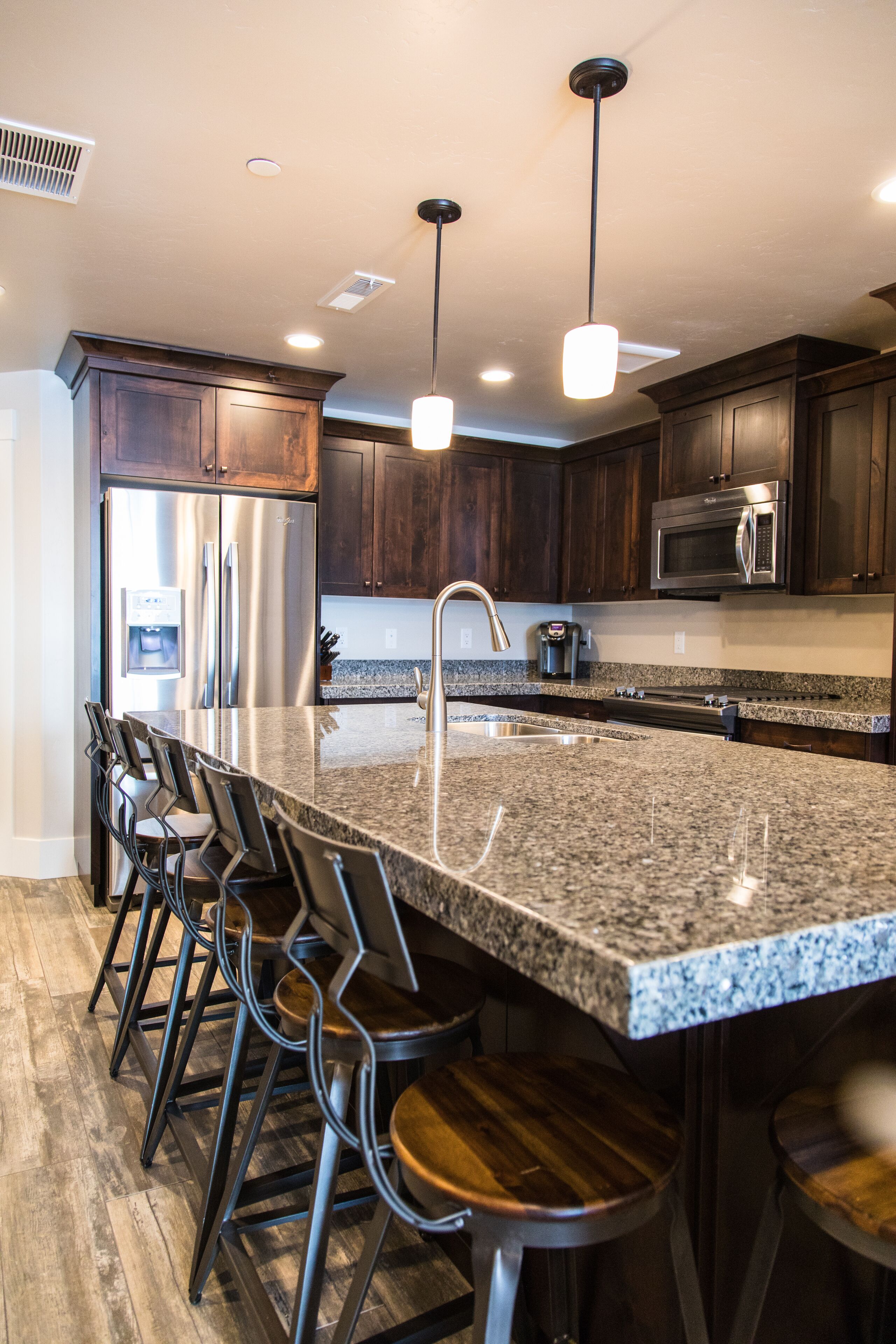 A modern kitchen with granite countertops, stainless steel appliances, and dark wood cabinets.