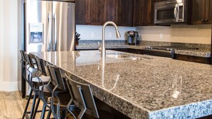A modern kitchen with granite countertops, stainless steel appliances, and dark wood cabinets.