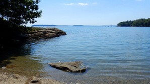 A clear lake with a rocky shoreline and a visible tree on the left. - Dramatic Oceanfront House w/ Private Swimming Cove & Dock (Freeport)