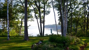 A serene lakeside garden with birch trees, a grassy area, and a small pond. - Dramatic Oceanfront House w/ Private Swimming Cove & Dock (Freeport)