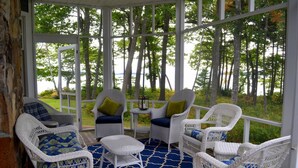 A covered outdoor seating area with wicker chairs and a blue patterned rug. - Dramatic Oceanfront House w/ Private Swimming Cove & Dock (Freeport)