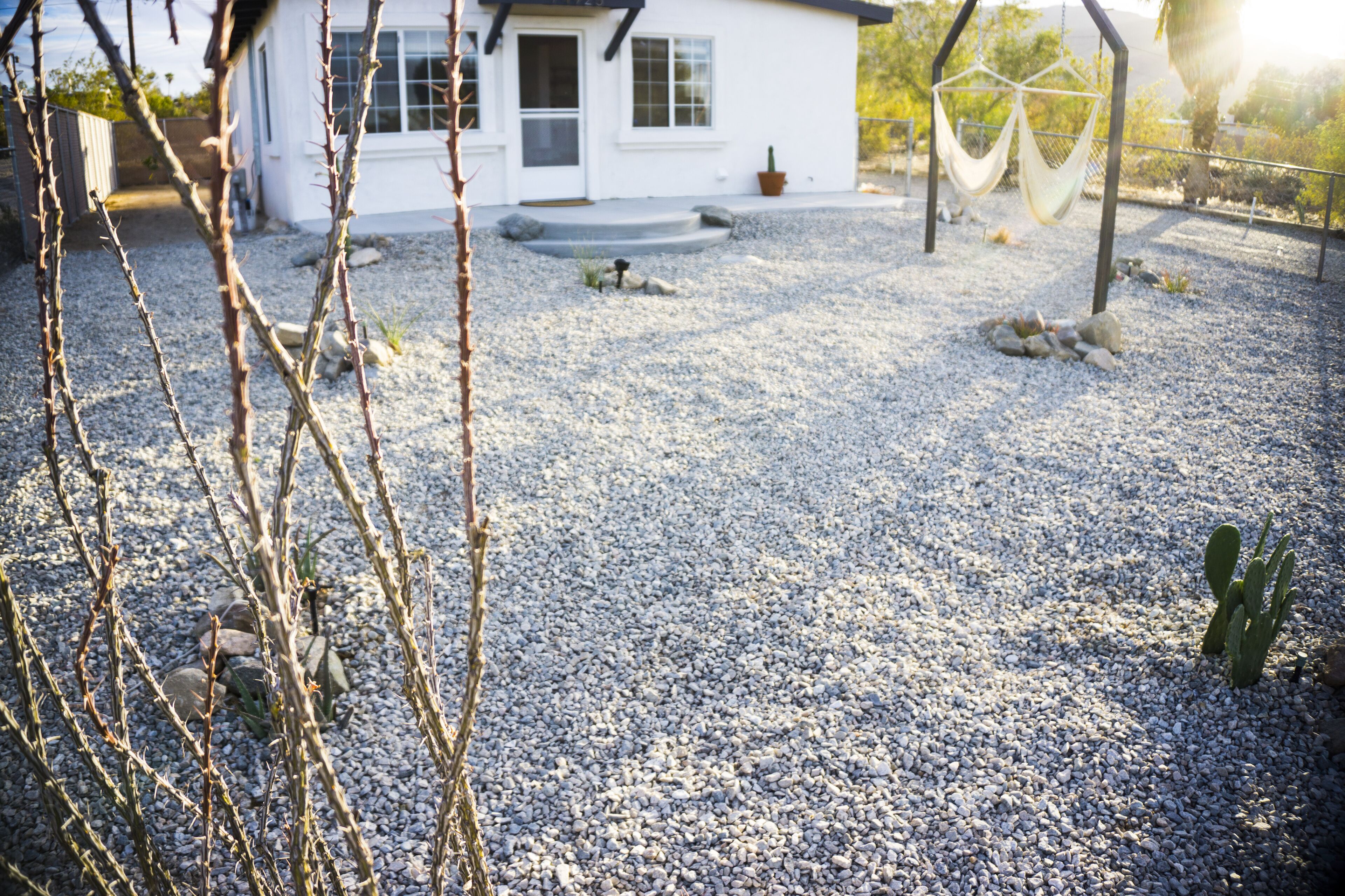 Ein Haus mit Kiesweg, einer Hängematte und einem Kaktus im Garten.