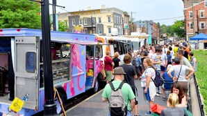 Une rue animée, avec des camions-restaurants et une foule de personnes.