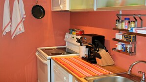 Une cuisine de taille réduite, avec des appareils électroménagers blancs, un plan de travail en bois et un mur rouge.