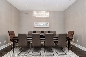 A conference room with a rectangular table, six chairs, a chandelier, and a framed picture on the wall.