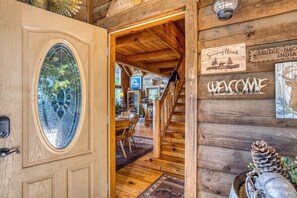 A wooden cabin interior with a stained glass door, a staircase, and a welcome sign. - Soaring Hawk The `Ultimate` Log Cabin with EPIC Breathtaking Views|Hot Tub|Pets Welcome (Sautee Nacoochee)