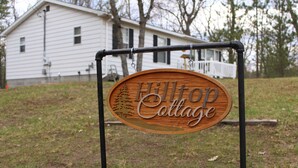 A wooden sign with the text "Hilltop Cottage" mounted on a metal frame.