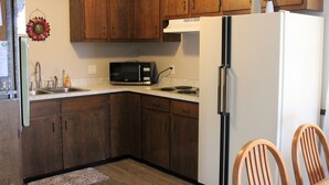 A kitchen with wooden cabinets, a white refrigerator, a microwave, and a sink.