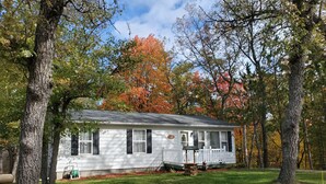 A single-story house with a front porch, surrounded by trees with autumn foliage.