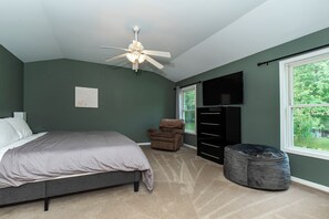 Une chambre à coucher avec un lit, une chaise, une commode et une fenêtre.