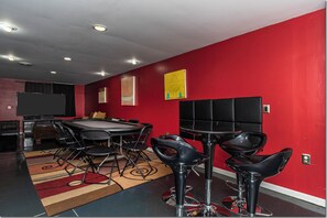 Une salle de conférence avec une table ronde, des chaises noires et un écran de télévision.