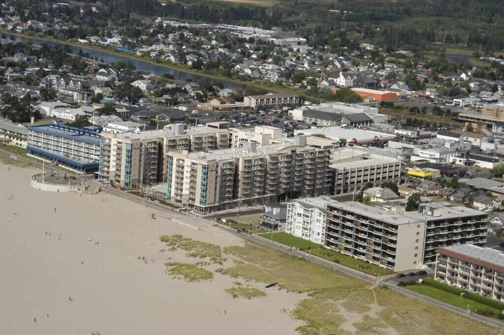A coastal hotel with multiple floors, a beach view, and a parking area.