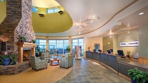 A spacious lobby with a stone fireplace, comfortable seating, a reception desk, and large windows offering views. - Luxury Vacation Condos at Seaside Oceanfront Resort (Seaside)